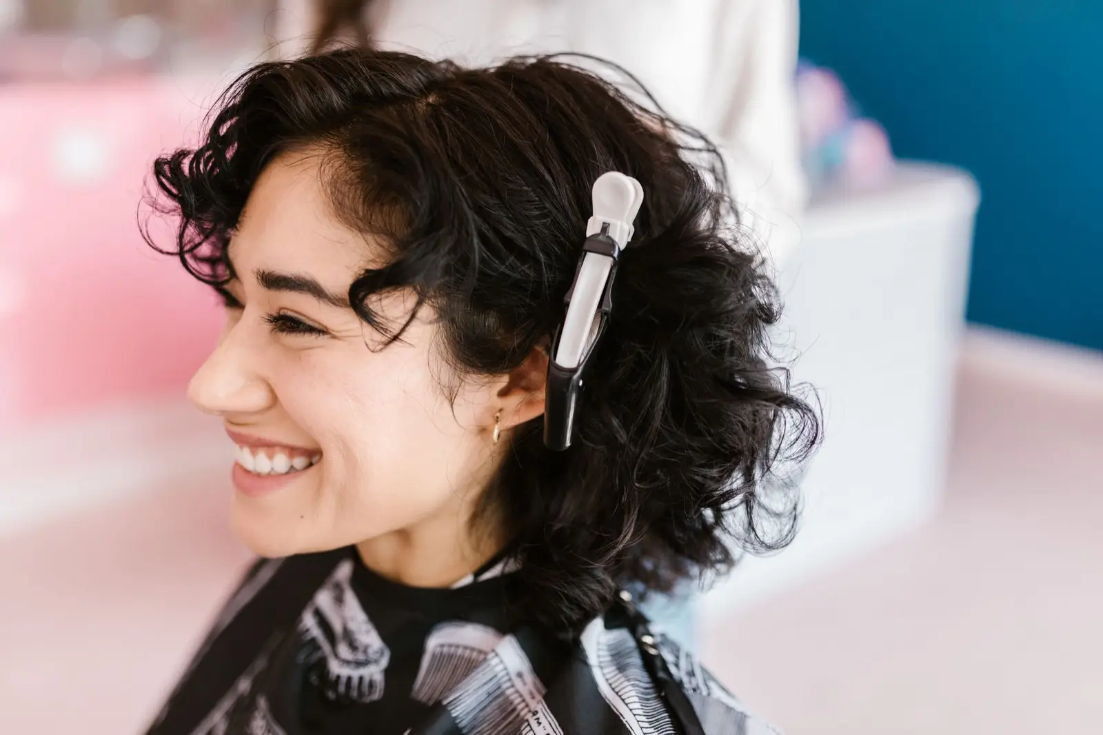 Lachende Kundin mit dunklen Locken und Haarklammer