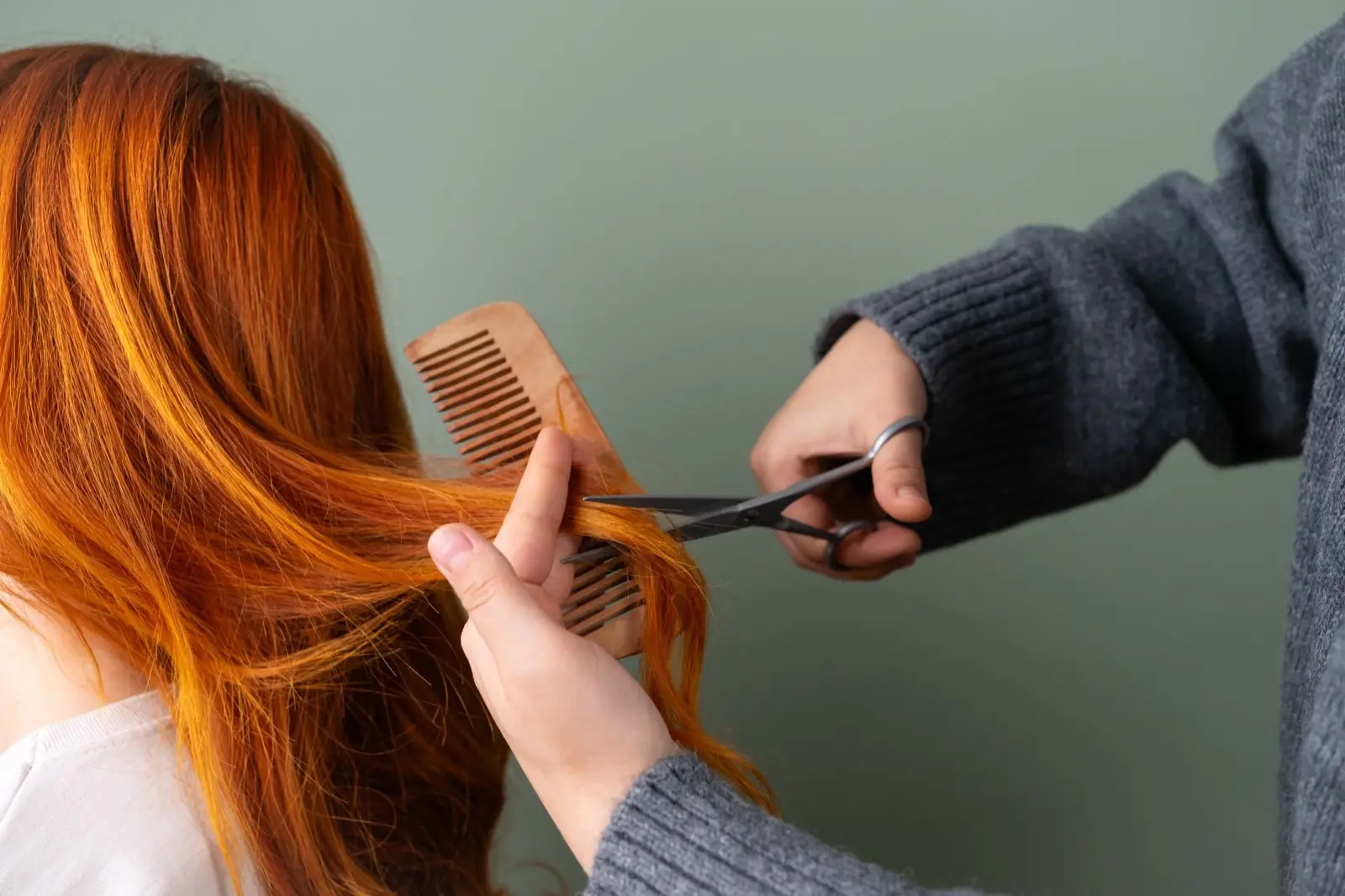 Kupferrote lange Haare werden mit Kamm und Schere geschnitten