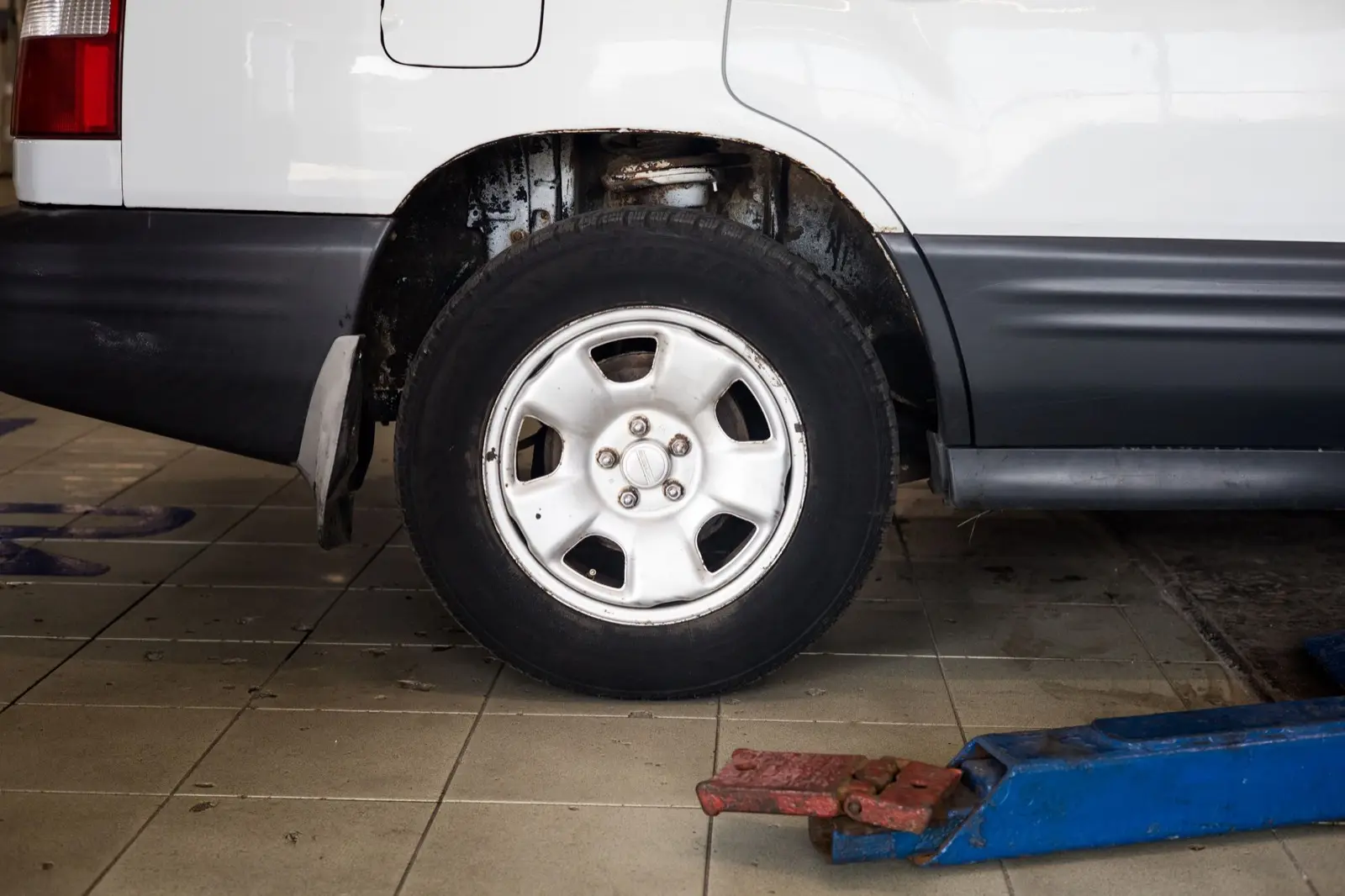 Rad eines Autos auf der Hebebühne in einer hellen Werkstatt