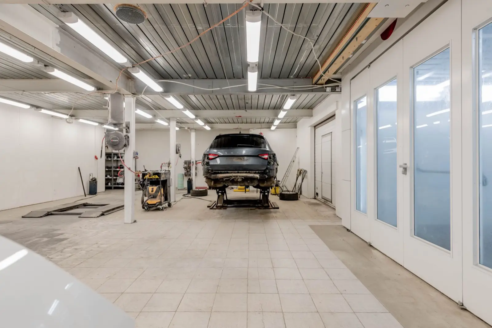 Helle, aufgeräumte Werkstatthalle mit Auto auf der Hebebühne