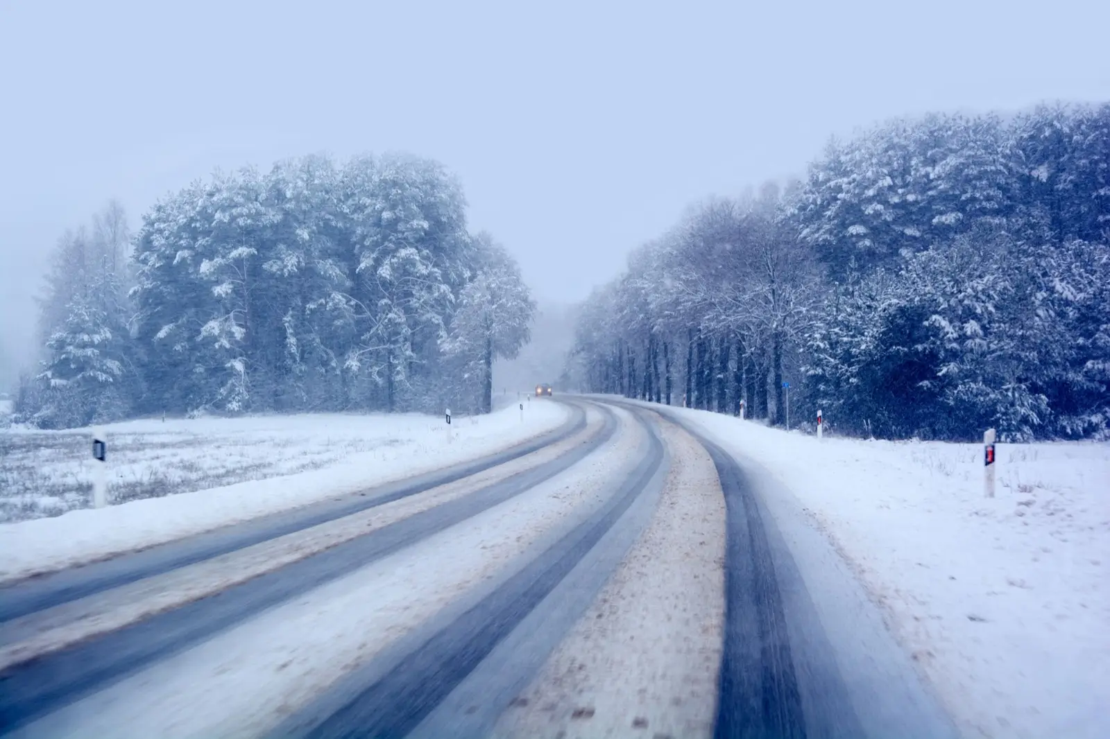 Verschneite Landstraße durch einen Winterwald