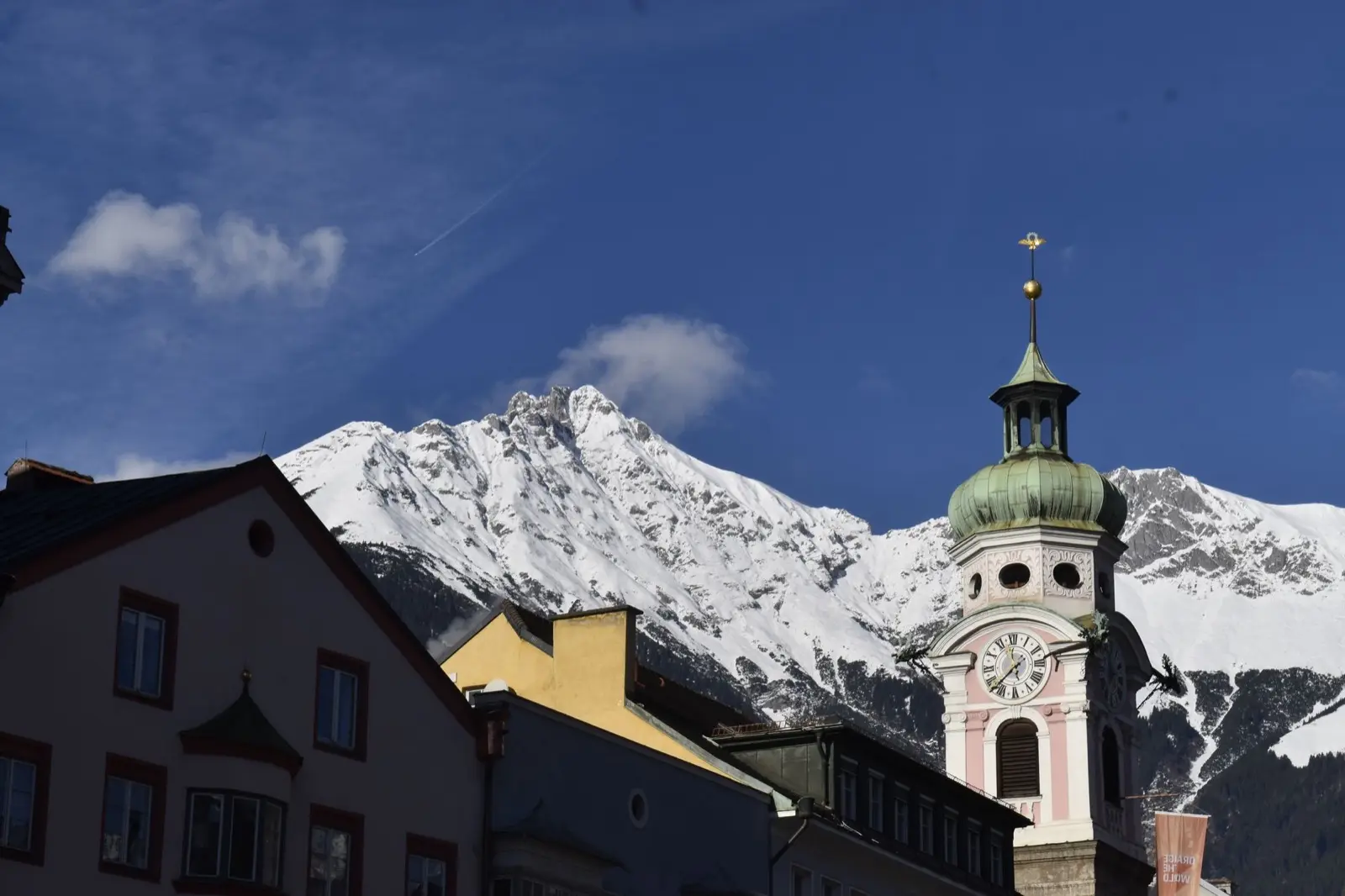 Barocker Kirchturm vor der verschneiten Nordkette bei Innsbruck